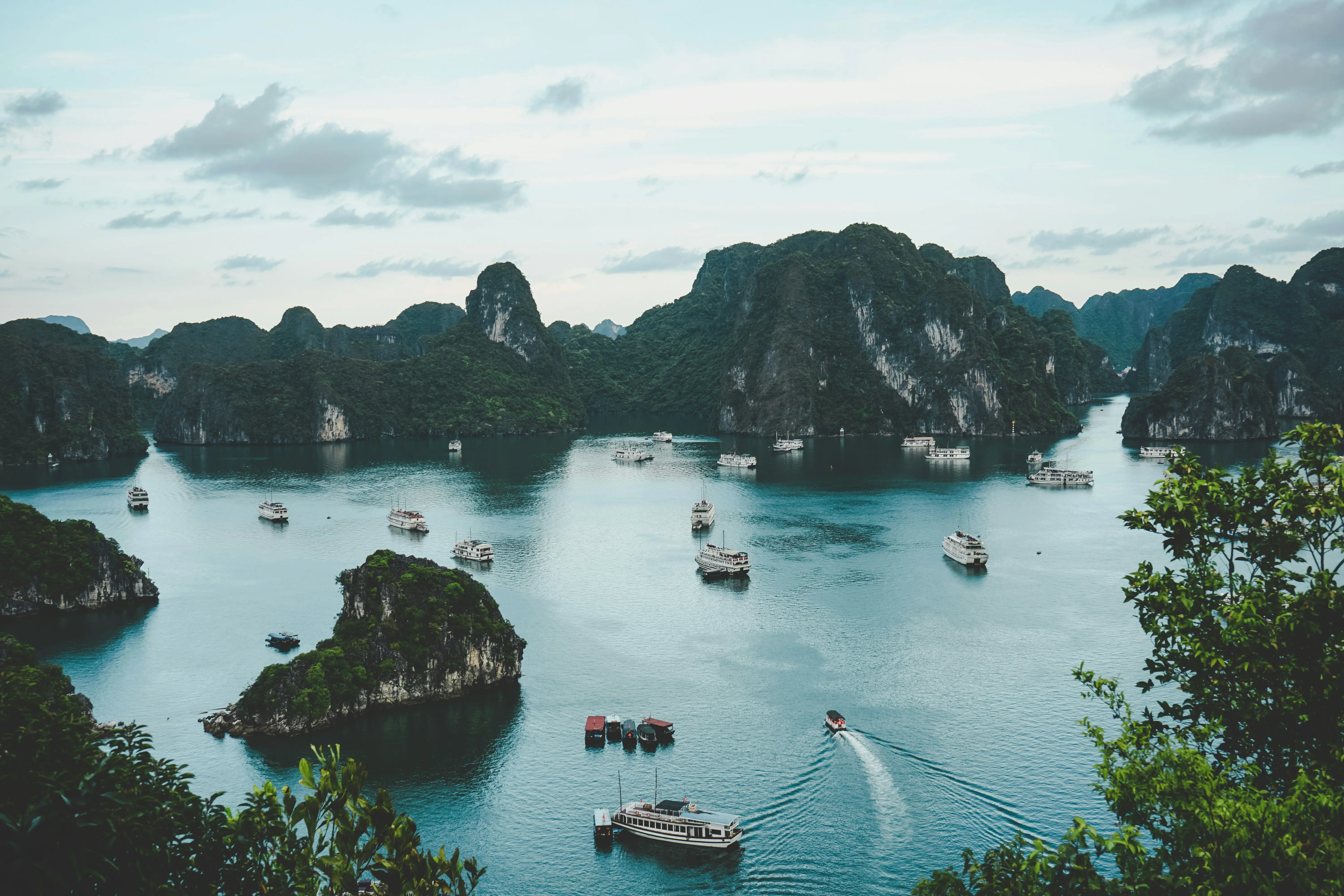 Traditional wooden junk sailing between towering limestone karsts in Halong Bay